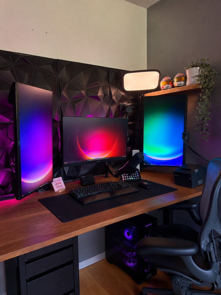 Stream setup van Romz met drie monitors, microfoon en paarse verlichting